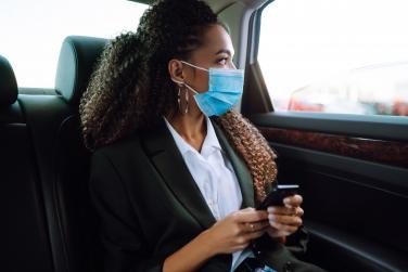Une infirmière masquée à l'arrière d'un taxi regarde à travers la vitre