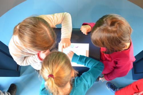 vue plongeante sur des enfants au-dessus d'une tablette tactile à l'Écopole Edelweiss
