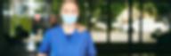 Une étudiante avec une blouse de soignant et un masque se tient debout dans un hall